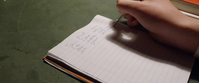 a person writing on a notebook with a pen