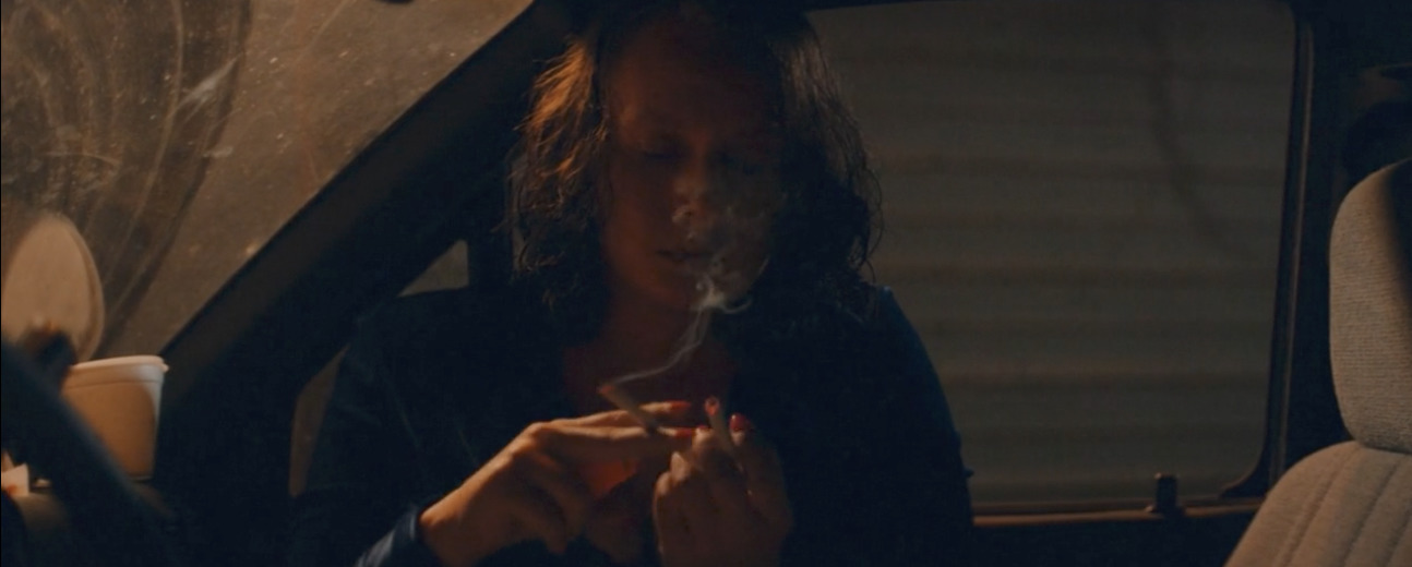 a woman sitting in a car smoking a cigarette