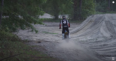 a man riding a dirt bike down a dirt road