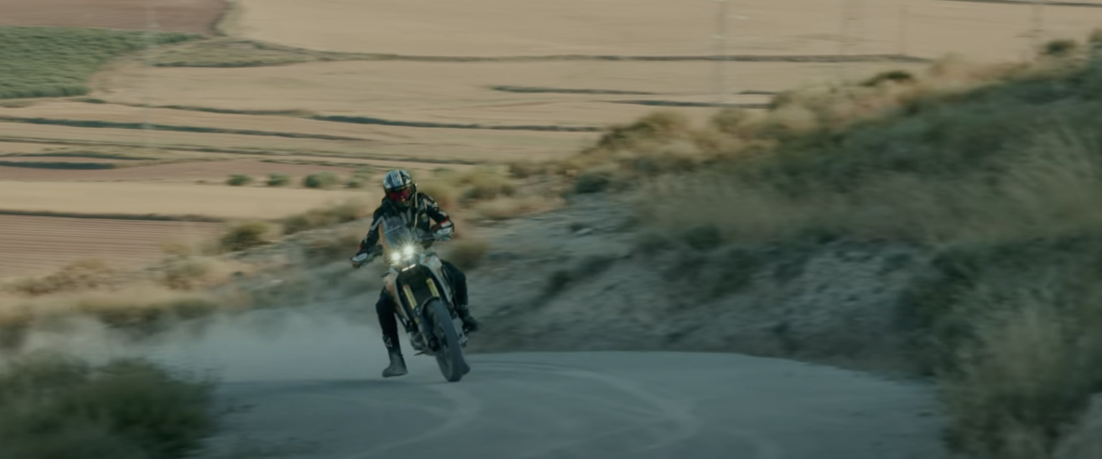 a man riding a motorcycle down a dirt road