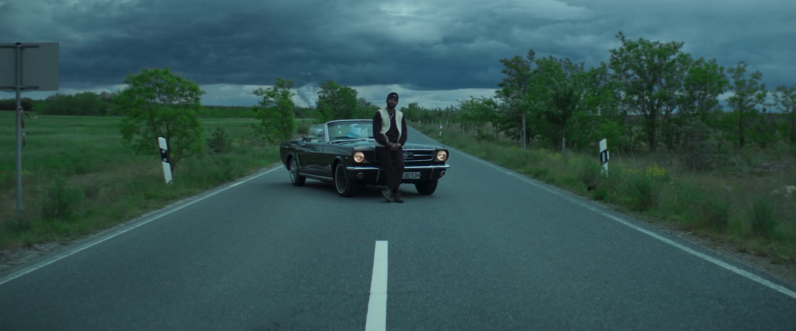 a man standing on the hood of a car on a road