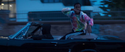 a man standing on top of a convertible car