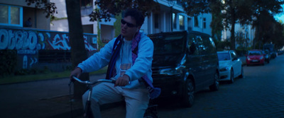 a man riding a bike down a street next to parked cars