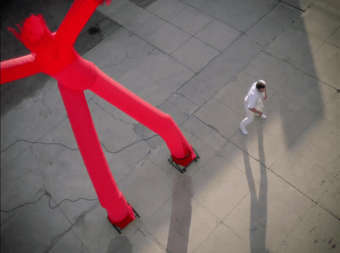 a man walking down a sidewalk next to a giant red object