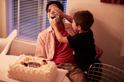 a man and a boy sitting at a table with a cake