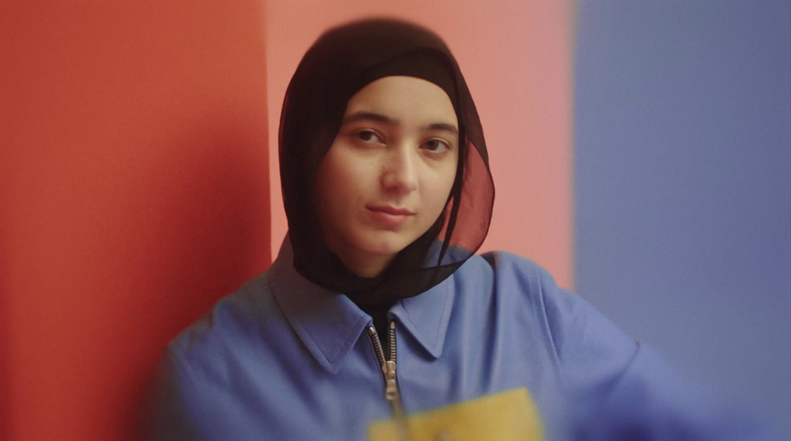 a woman wearing a blue shirt and a black hoodie