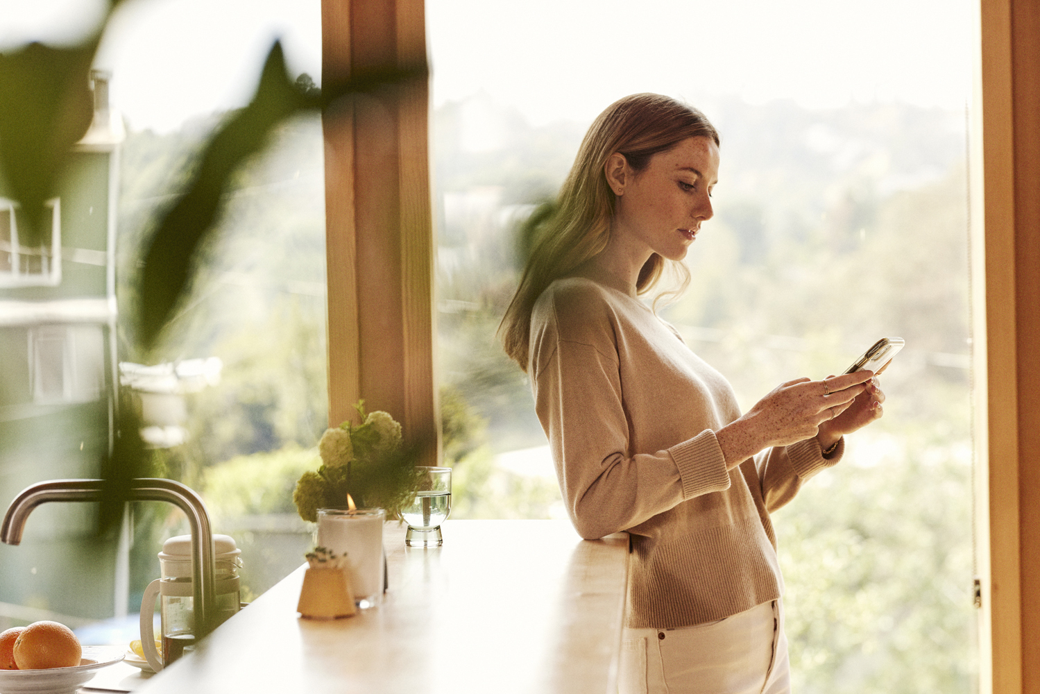 a woman standing in a kitchen looking at her cell phone