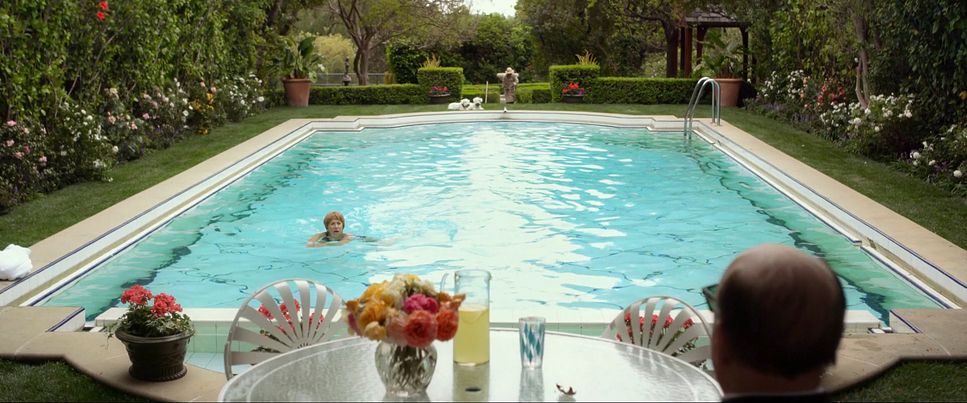 a woman sitting at a table in front of a swimming pool