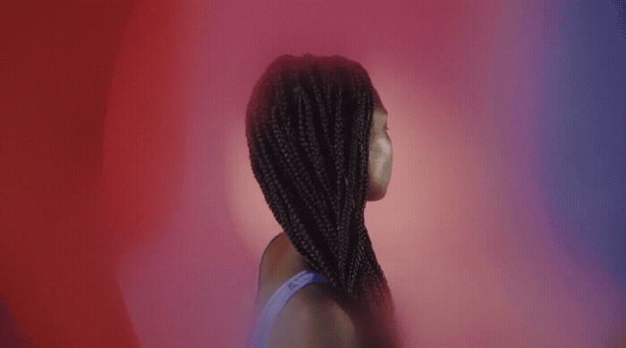 a woman with long braids standing in front of a red and blue background