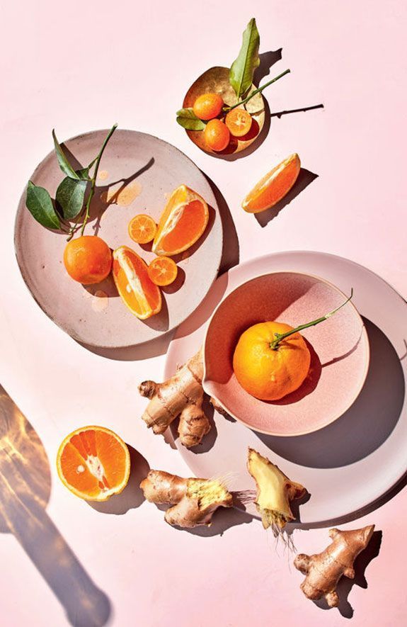 a table topped with plates of oranges and ginger