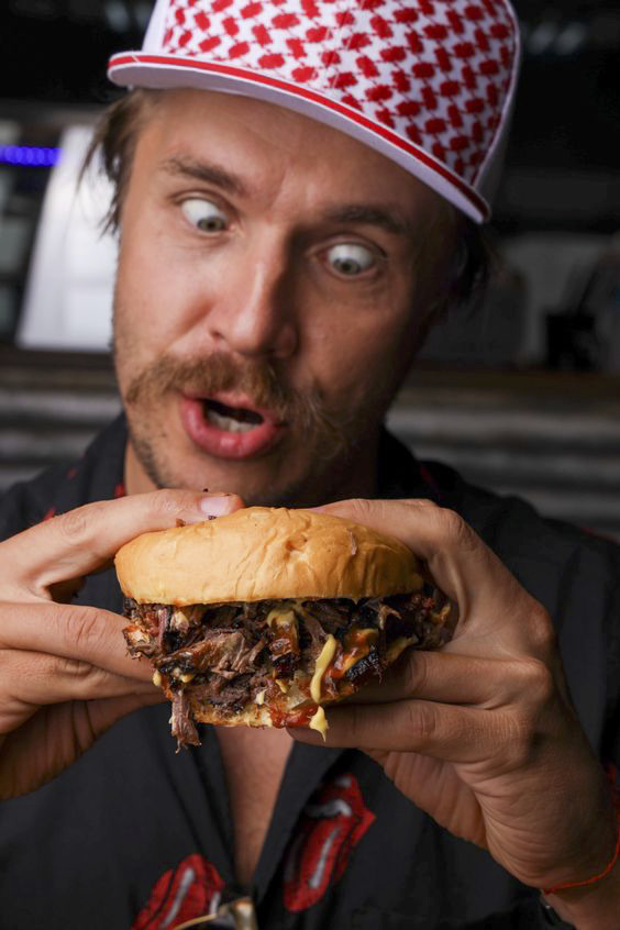 a man in a red and white hat is holding a sandwich