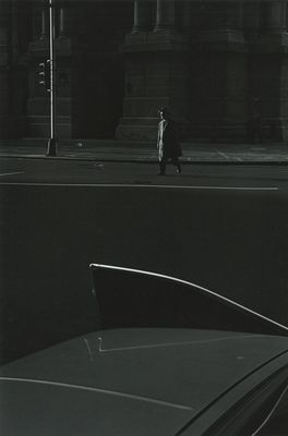 a black and white photo of a man walking down a street