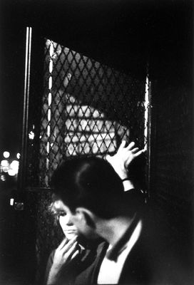 a woman leaning against a chain link fence