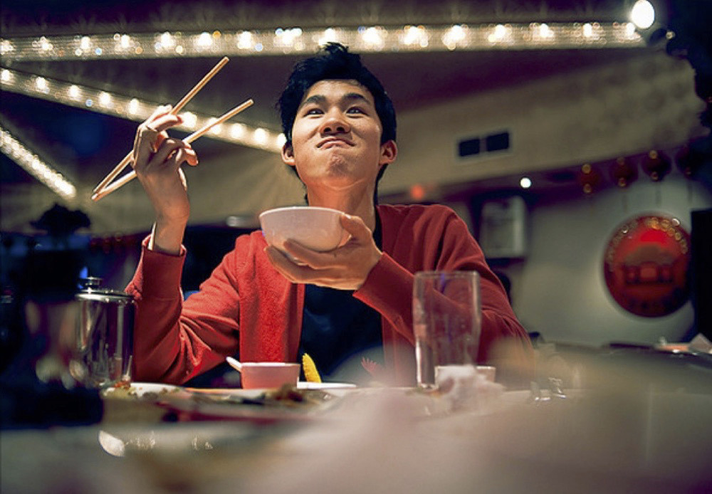 a man sitting at a table with chopsticks in his hand