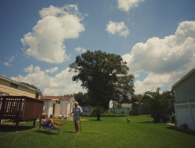 a man standing in a yard next to a tree