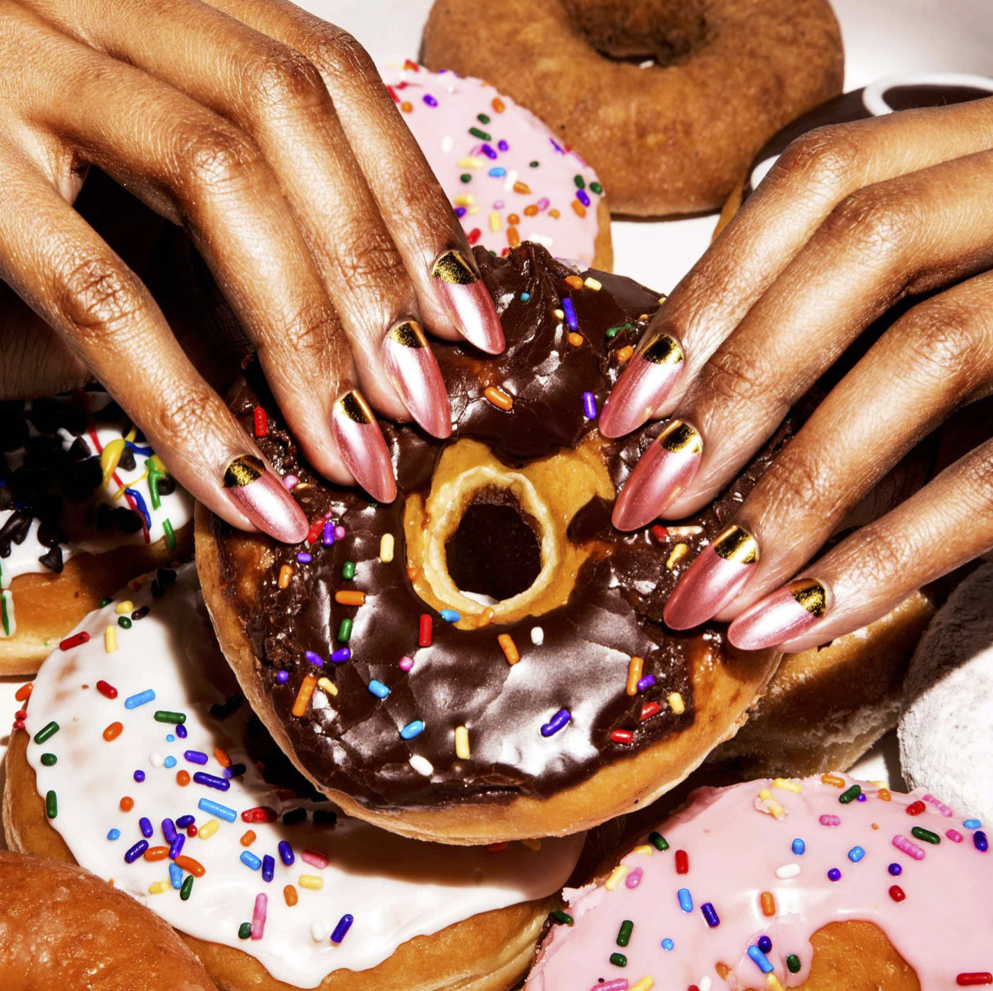 a close up of a person holding a doughnut with sprinkles