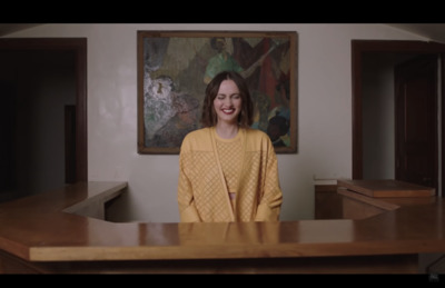 a woman standing in front of a wooden desk