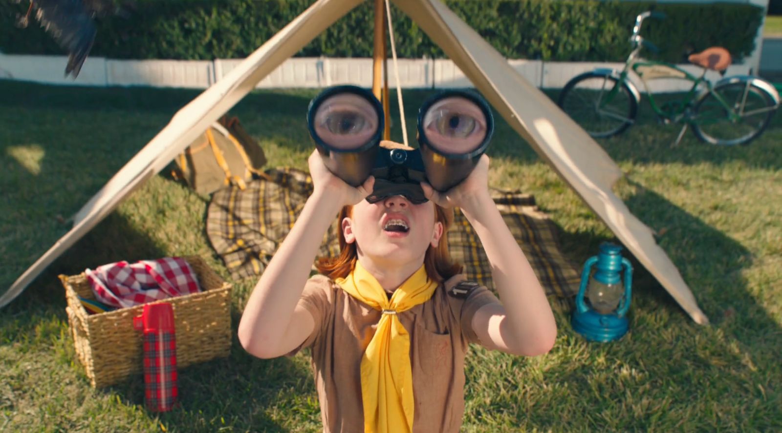 a young girl wearing a yellow scarf is looking through a pair of binoculars