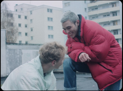 a man in a red jacket is talking to another man