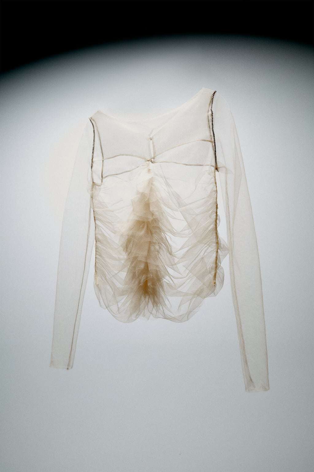 a white shirt with a feather hanging from it's back