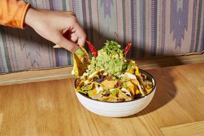 a person dipping a tortilla into a bowl of guacamole