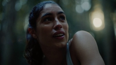 a woman in a white tank top in a forest