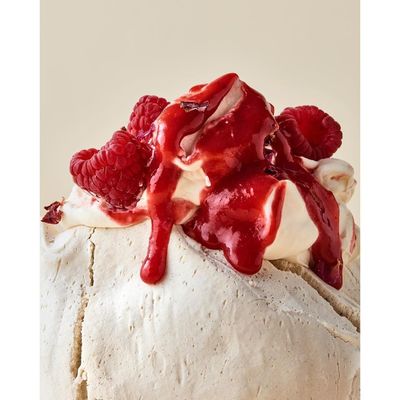 a cake covered in raspberries and whipped cream