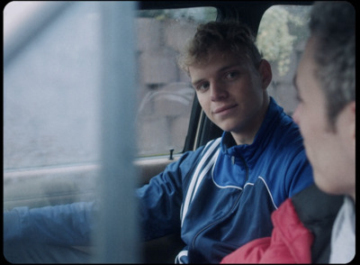 a man sitting in a car with another man behind him