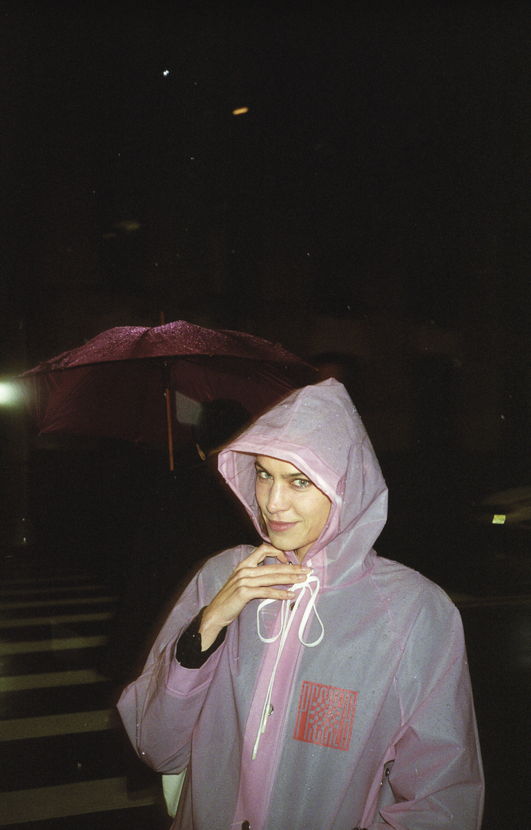 a woman in a pink raincoat is holding an umbrella