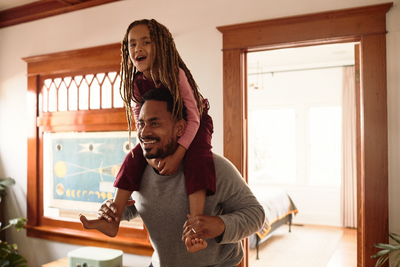 a man holding a little girl on his shoulders