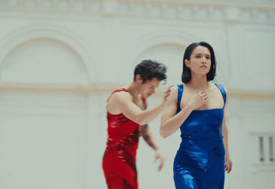 a woman in a red and blue dress standing next to a man in a red