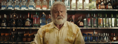 a man standing in front of a shelf filled with bottles