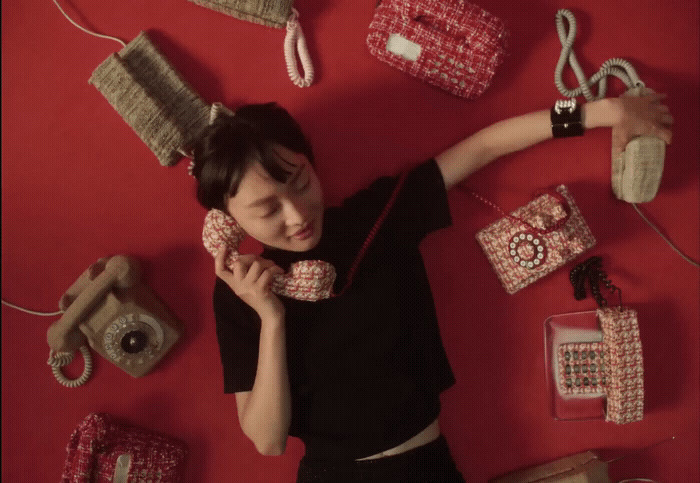 a woman laying on the ground surrounded by purses and cell phones