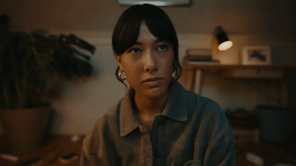 a woman in a dark room with a plant in the background