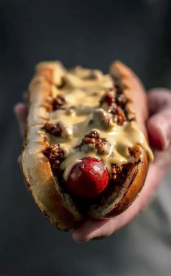 a person holding a hot dog in their hand