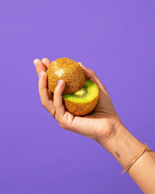 a person holding a kiwi fruit in their hand