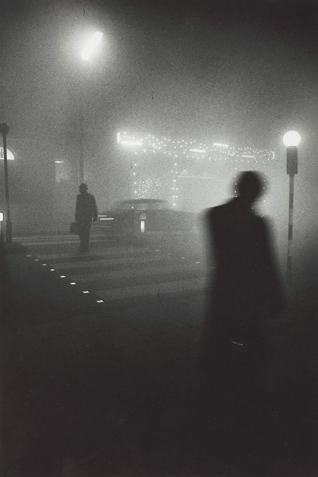 a black and white photo of a person walking in the fog