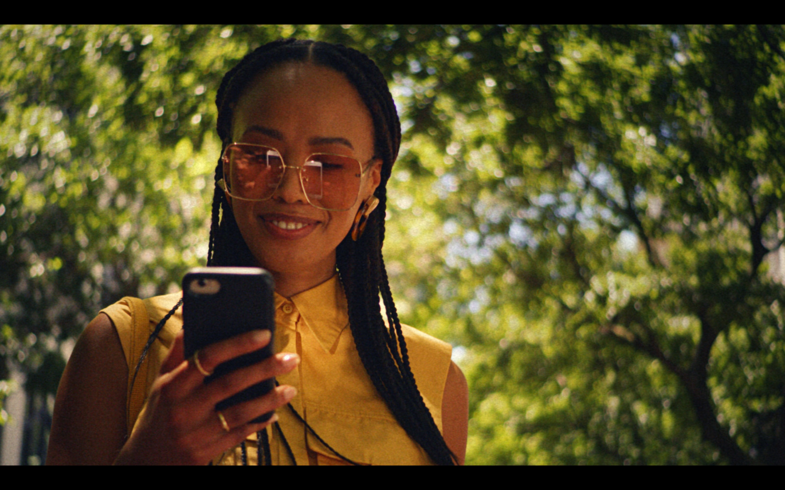 a woman in a yellow shirt is looking at her cell phone