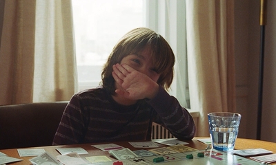 a young boy sitting at a table with a glass of water in front of him