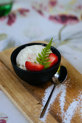 a bowl of rice and a strawberry on a wooden board