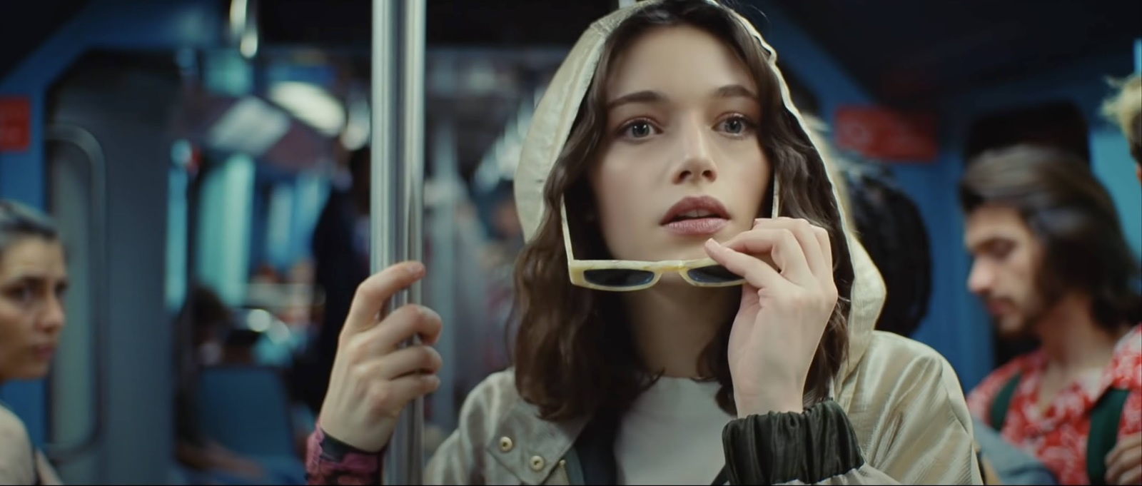 a woman in a hooded jacket eating food on a train