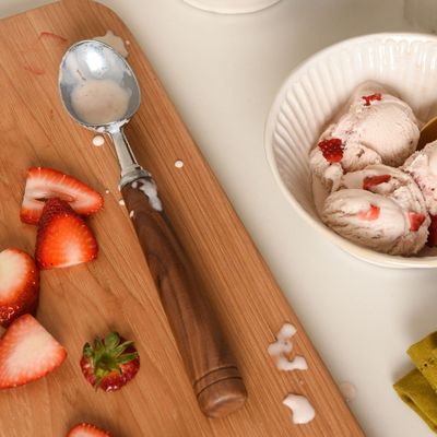 a bowl of ice cream with strawberries on a cutting board