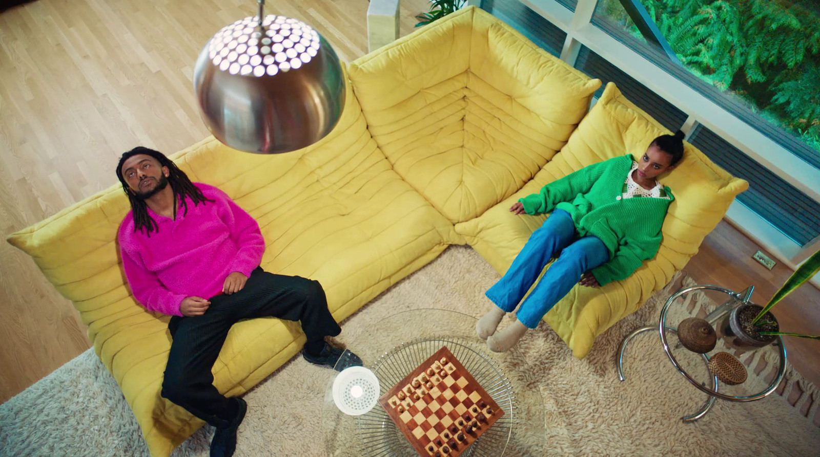 two men sitting on a yellow couch in a living room