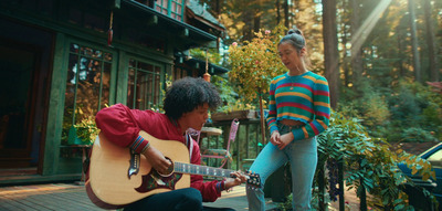 a man playing a guitar next to a woman