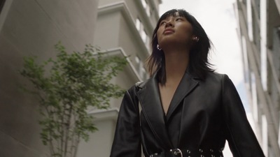 a woman in a black jacket is standing in front of a building