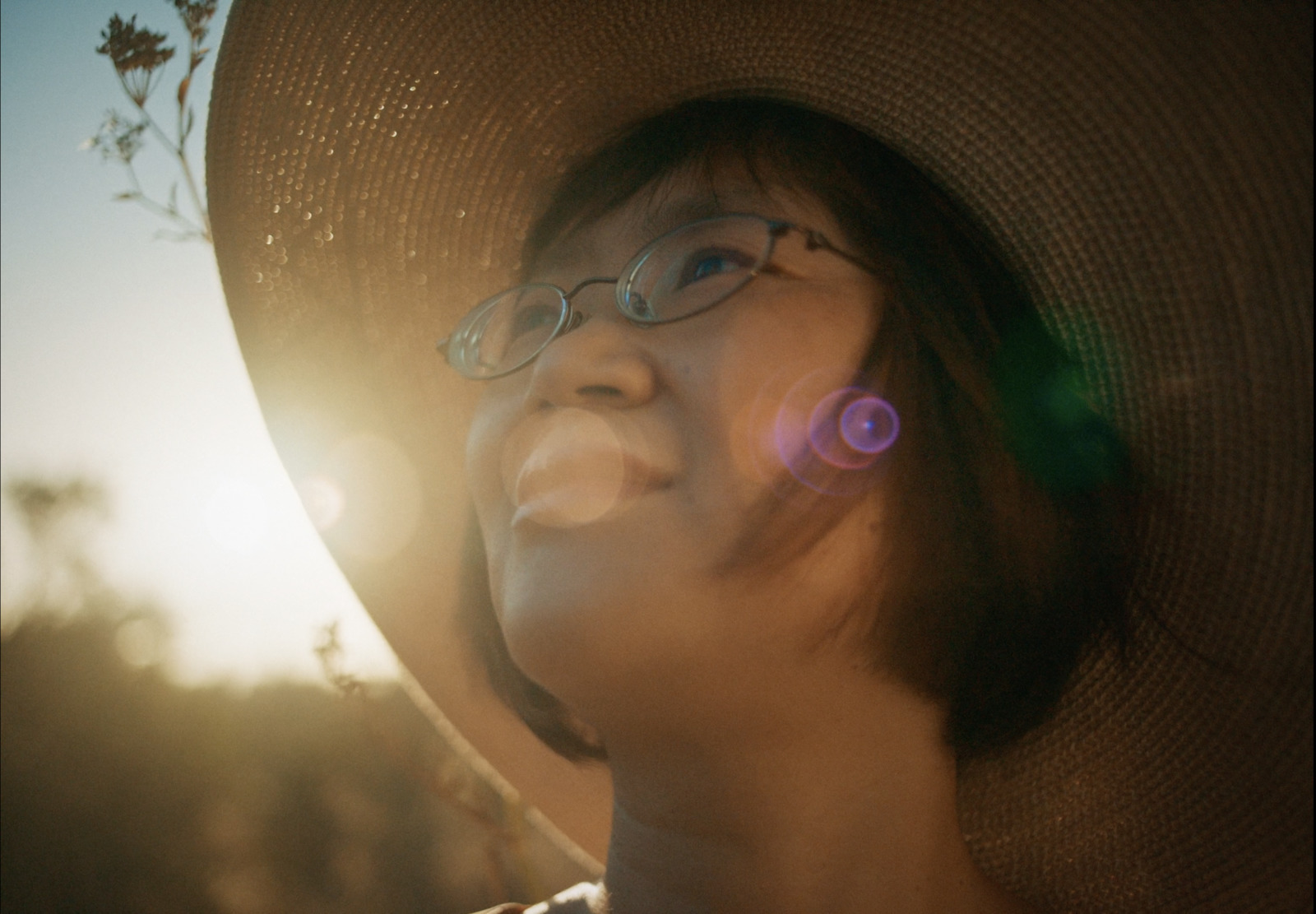 a woman wearing a hat and glasses is smiling