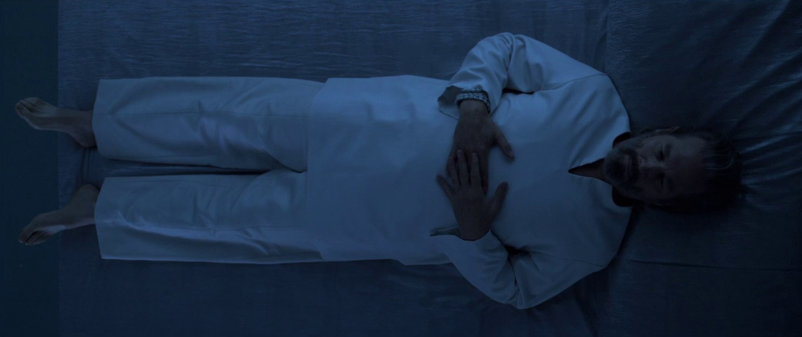 a man in a white shirt laying on a bed