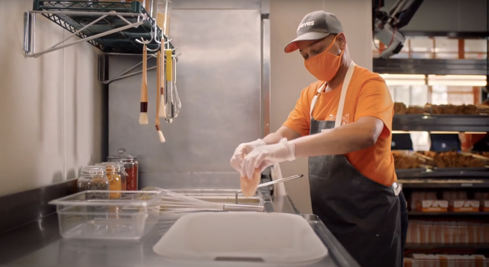 a person in an orange shirt and a hat in a kitchen