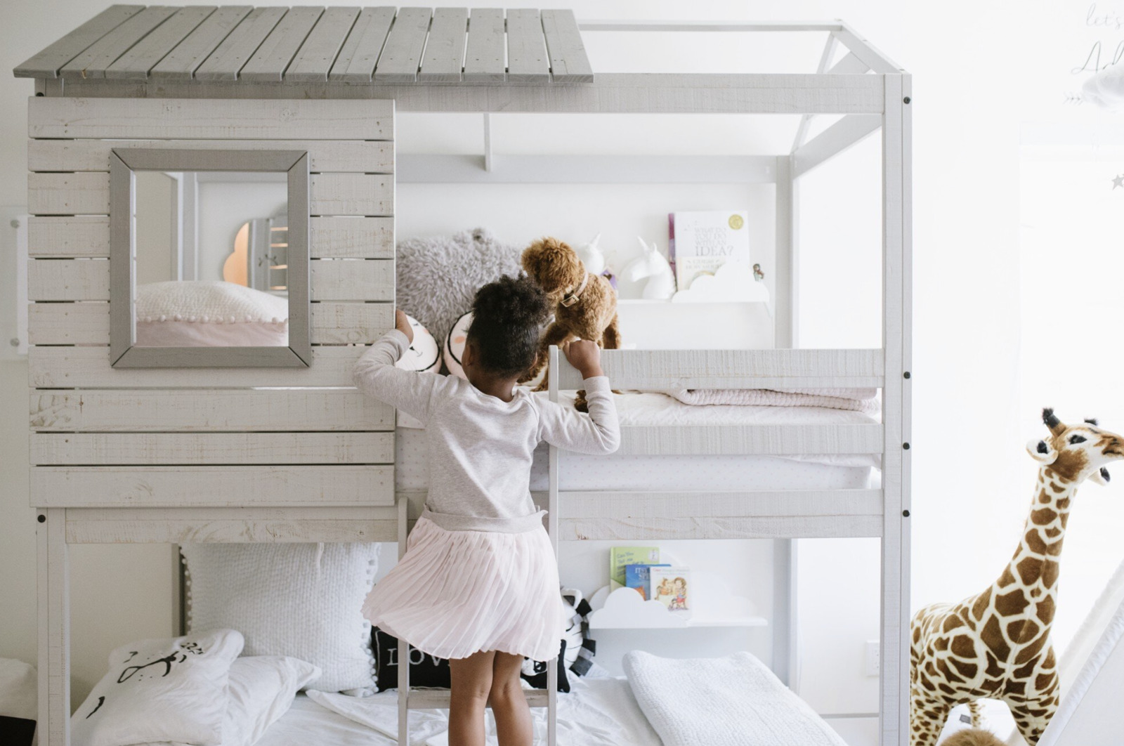 a little girl that is standing on a bunk bed