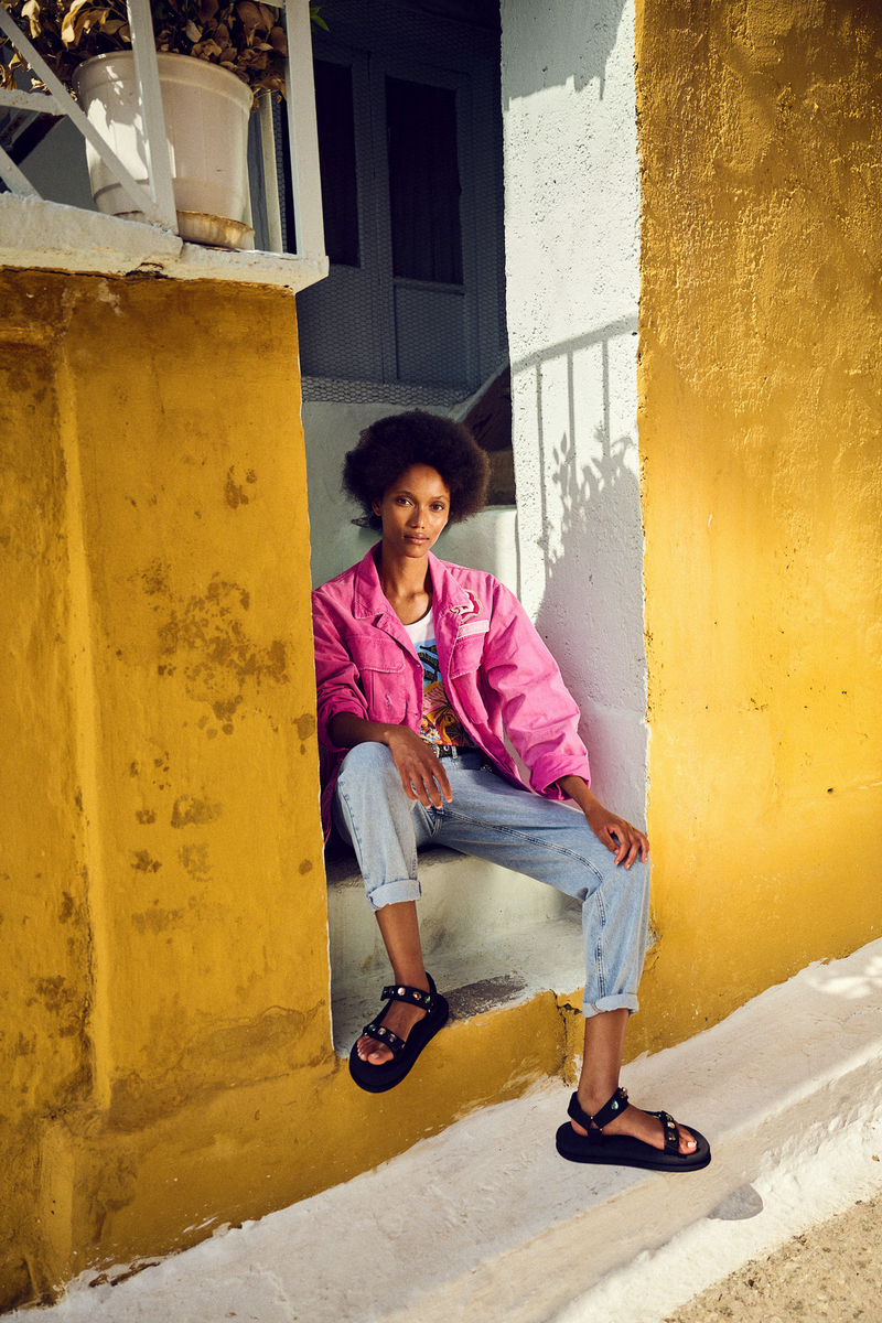 a woman in a pink jacket is sitting on a ledge